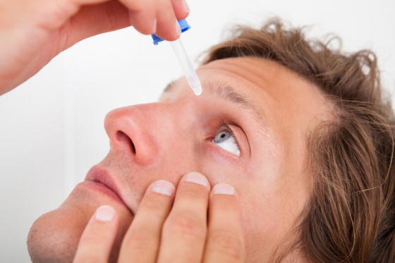 man putting eyedrops in his eye to manage glaucoma